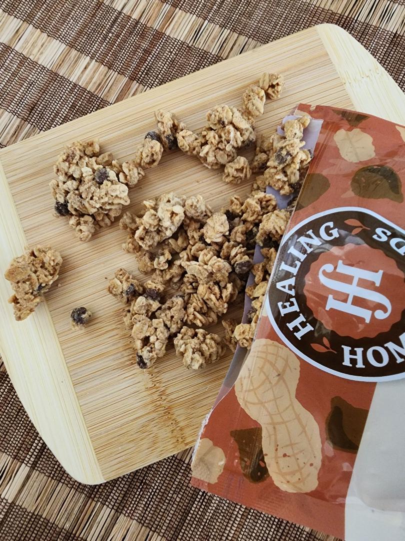 Granola clusters on a wooden board with a 'Healing Hands' package.
